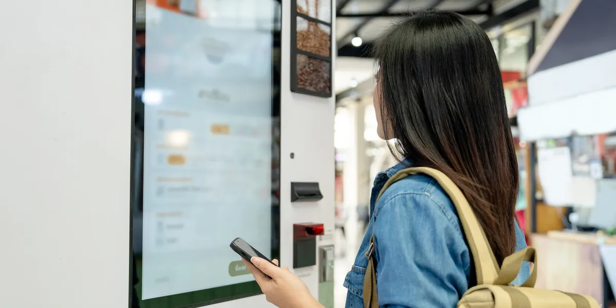 Kundin interagiert mit einem modernen Verkaufsautomaten